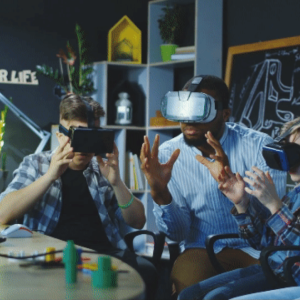 An adult and three children wearing vr headsets and holding hand out in a ball shape in a classroom setting.