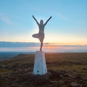 A person doing a pose on top of a small pillar in an open area.