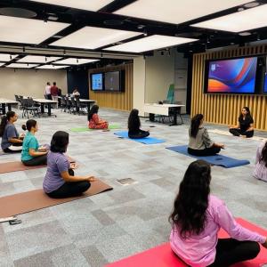 A group of people each on a mat in a large open room, one leading at the front.