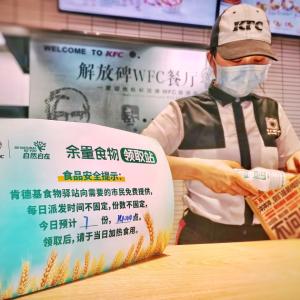 KFC China worker bags food next to a sign for the food bank