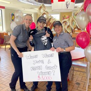 3 KFC employees hold a sign that reads " Winner, Winner. You're a REACH  grant winner! $3,000!"