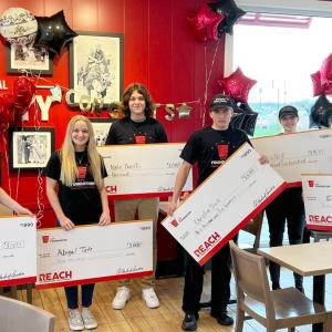 6 students holding big checks