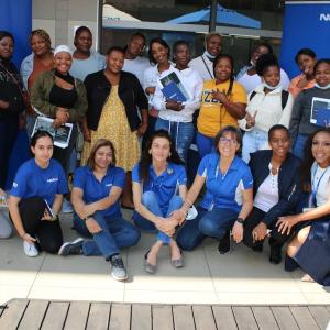 outside a group of people sit and stand, some holding paperwork, nokia banner behind them