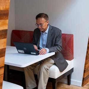 Zhang working on a laptop at a booth seat