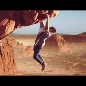 man hanging from mountainous rockface looking down