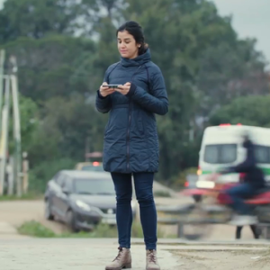 A woman in a blue coat standing outside holding a cell phone