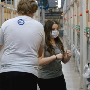 Image of a woman wearing a face mask and a man walking towards her with his back turned to the camera