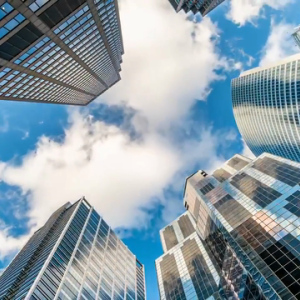 Photo of a blue sky looking up through a group of skyscrapers.