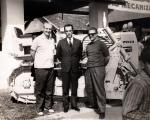 old photo of three people in front of bulldozer