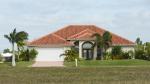 Palm trees and lawn in front of a stucco house with a red tiled roof.