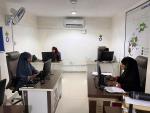 Three women work at desks in a white room in the call center. 