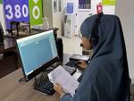 Sahra Ibrahim, a call center assistant, is wearing a headset to take phone calls while working on her computer. 