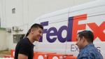 Two people talking and smiling next to a FedEx Express van and Direct Relief boxes