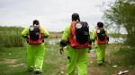 Three people seen from the back walking away, in high-vis suits with Direct Relief backpacks