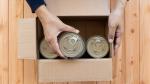 Hands packing canned food into a box
