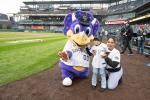 Colorado Rockies mascot with a child and adult on a baseball field