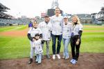 A group of people in Rockies shirts on a baseball field posing for the camera
