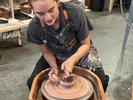 Natalie seated at a potters wheel.
