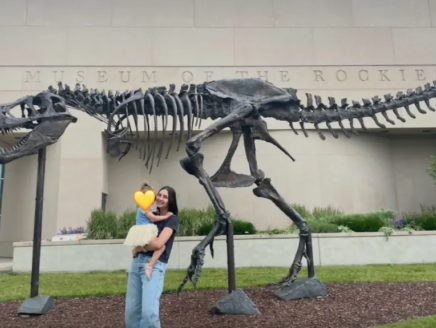 Natalie and her daughter in front of a fossil of a dinosaur.