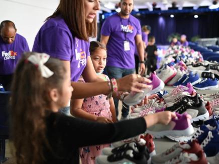 Children and volunteers in front of a table full of shoes