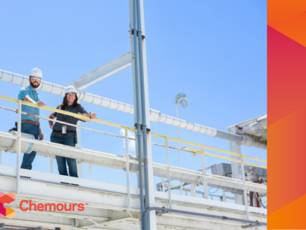 Two people in hard hats standing on a high walkway