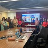 A group of people smiling and standing together in a board room in front of a large screen