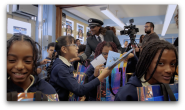 American Airlines pilot speaking with a group of children holding the Bessie Coleman doll 