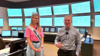Grace wearing a crown and sash, and a representative from Southern Company in a room full of screens