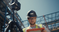 Worker in hardhat consulting tablet at a construction site