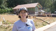 Person speaking in front of house being rebuilt