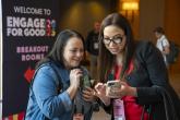 Two conference participants huddled over a cell phone at Engage for Good 2025
