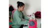 Jyoti sat at a desk using a sewing machine 
