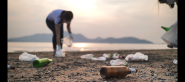 Two people picking up trash on a beach.