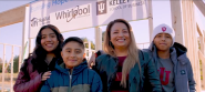 A parent and three kids in front of a new home-build site