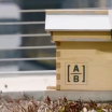 Wooden beehive with AB logo on the side.