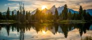 body of water with trees and mountains in the background