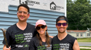 Three volunteers posed in front of a house under construction.