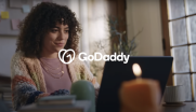 GoDaddy: Female seated in front of a laptop.