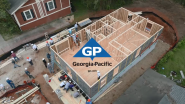 Aerial view of a home being built, many people at the site. Georgia-Pacific logo on top.