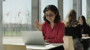A person sat at a table waving at their laptop
