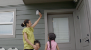Family standing by front door waving at camera