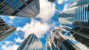 Photo of a blue sky looking up through a group of skyscrapers.