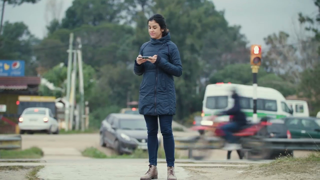 A woman in a blue coat standing outside holding a cell phone