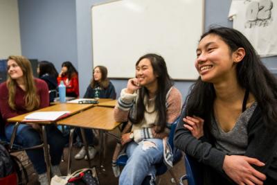 Franklin High students Jill Kumasaka, center, and Julie Pham, right, laugh as Microsoft CFO Amy Hood speaks to female students at the Seattle school on International Women’s Day, Thursday, March 8, 2018. (Photo by Dan DeLong)