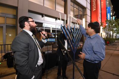AEG Vice President of Communications Michael Roth (right) lights the menorah in celebration of the eighth night of Chanukah at L.A. LIVE on December 19, 2017.