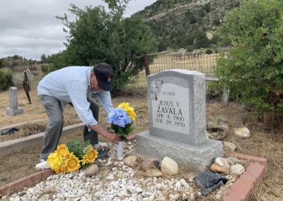 Edward Zavala of Raton, N.M. replaces artificial flowers at the grave of his father, Jesus V. Zavala, at Dawson Cemetery. Edward says his dad was the last miner to be buried in the cemetery before the town closed in 1950. (Nick Pappas/Albuquerque Journal)