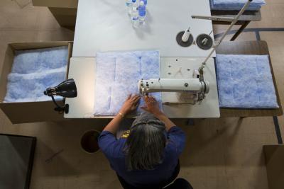 General Motors is recycling and processing two-million water bottles from Flint, Michigan residents and converting them into insulation for coats for the homeless, Chevrolet Equinox V-6 engine covers, and air filter panels for ten GM plants. The plastic is washed, flaked and turned into fleece to make these three products. Seamstresses Tameka Davis and Dorothea Guice sew the filter panels at the N.E.W. Life Center for GM supplier Filtration Services Group in Flint, Michigan. (Photo by Jeffrey Sauger for General Motors)