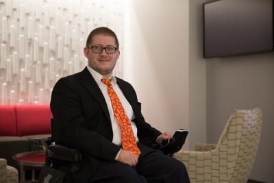 Image Description: Eric Wright smiles. Eric is wearing a suit and using a power wheelchair. Eric Wright, Senior Lead Technologist at Booz Allen Hamilton and member of the firm’s Global Disabilities business resource group (BRG)