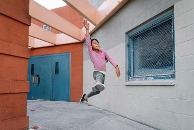 A young girl leaps through the air during a Red Eye mentoring session at the Watts Empowerment Center. Photo by Erin Sullivan for Red Eye.