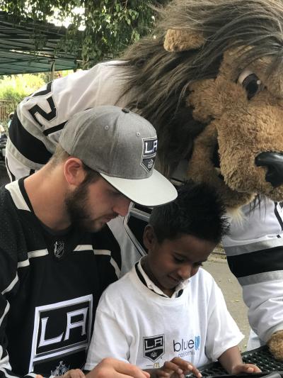 LA Kings forward Kyle Clifford (left), LA Kings mascot, Bailey and a student from St. Anthony explore G.O.A.L.S., a digital platform that helps equip children in Los Angeles with resources to be eco-friendly, inclusive, healthy, socially responsible and knowledgeable, on a tablet on November 8, 2017.